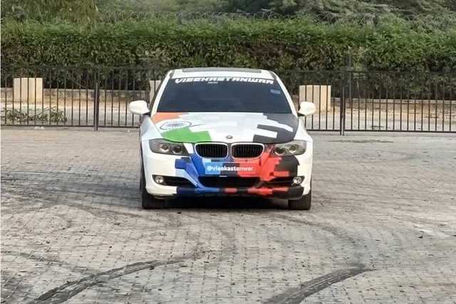 The school's BMW E90 in its white, saffron, green and blue livery, from the front